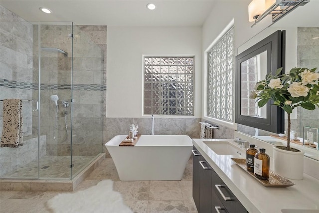 bathroom featuring vanity, separate shower and tub, and tile walls