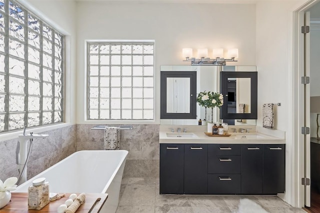 bathroom featuring vanity, a tub to relax in, a wealth of natural light, and tile walls