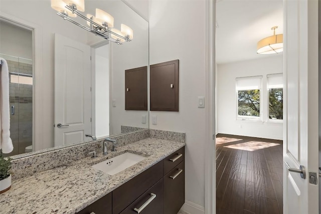 bathroom with hardwood / wood-style flooring, vanity, walk in shower, and toilet