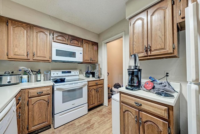 kitchen with white appliances, light hardwood / wood-style flooring, and a textured ceiling