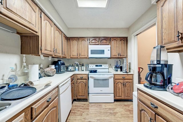 kitchen with white appliances, light hardwood / wood-style flooring, and a textured ceiling