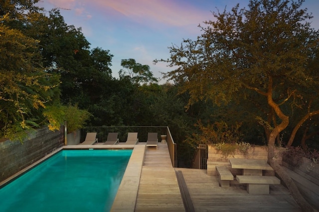 pool at dusk with a wooden deck