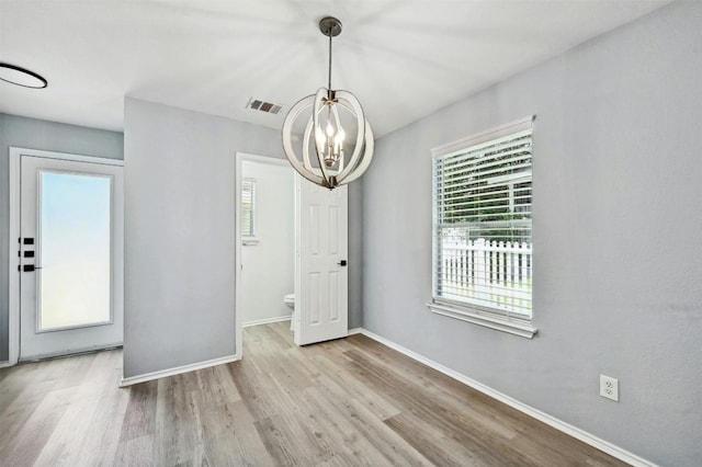 spare room with a chandelier and light wood-type flooring