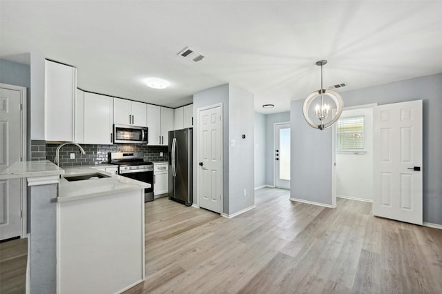 kitchen featuring sink, tasteful backsplash, appliances with stainless steel finishes, pendant lighting, and white cabinets