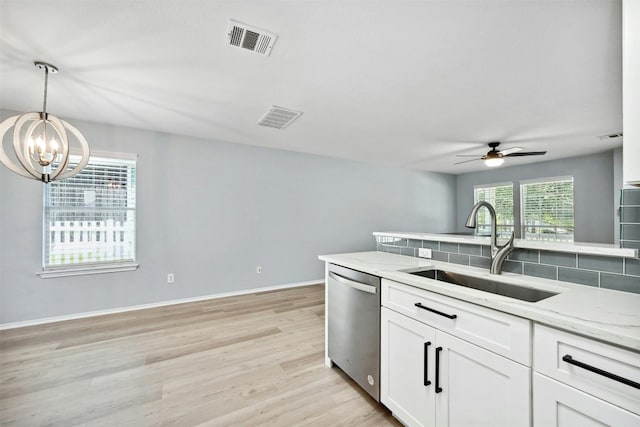 kitchen with light stone counters, dishwasher, sink, and white cabinets