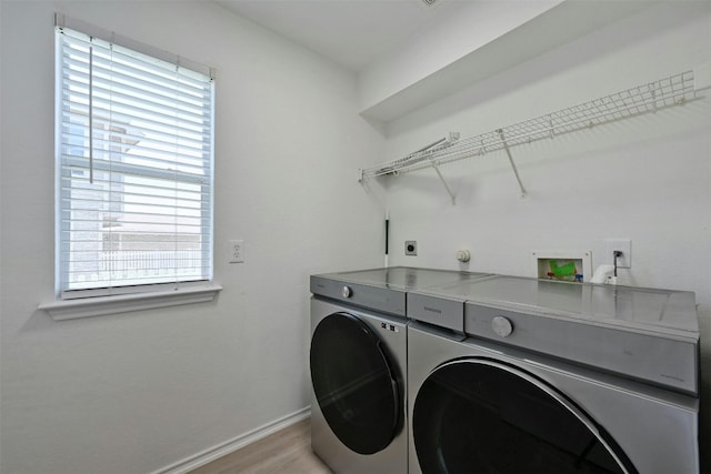 laundry area featuring washing machine and clothes dryer and light hardwood / wood-style floors