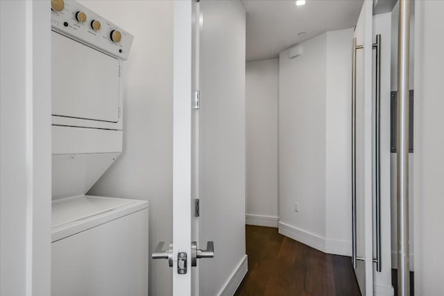 laundry area featuring dark wood-type flooring and stacked washer / dryer