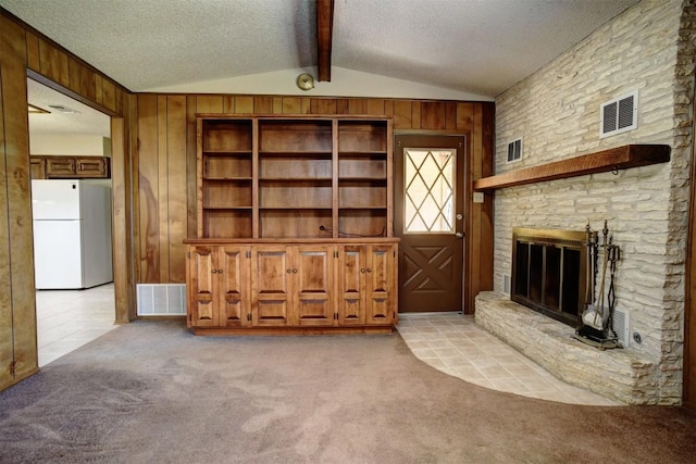 unfurnished living room featuring vaulted ceiling with beams, light colored carpet, a textured ceiling, and wood walls