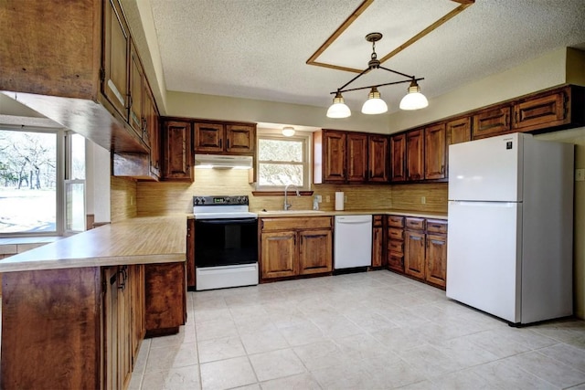 kitchen with pendant lighting, tasteful backsplash, sink, kitchen peninsula, and white appliances