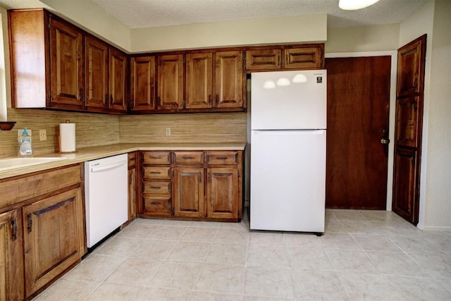 kitchen featuring white appliances, decorative backsplash, a textured ceiling, and light tile patterned flooring