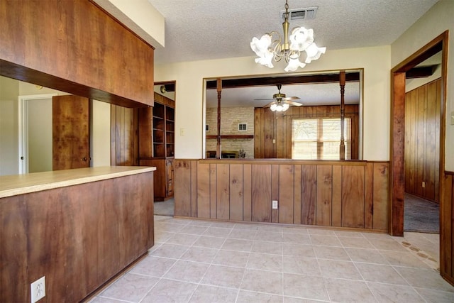 interior space featuring hanging light fixtures, light tile patterned floors, wooden walls, and a textured ceiling