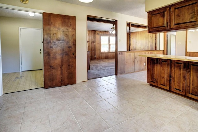 kitchen featuring a textured ceiling, wooden walls, and ceiling fan