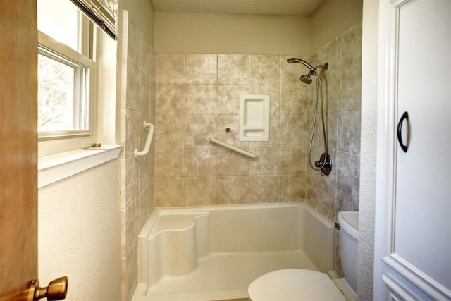 bathroom featuring a tile shower and toilet