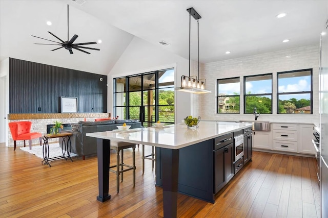 kitchen featuring pendant lighting, sink, light hardwood / wood-style flooring, white cabinets, and a kitchen island