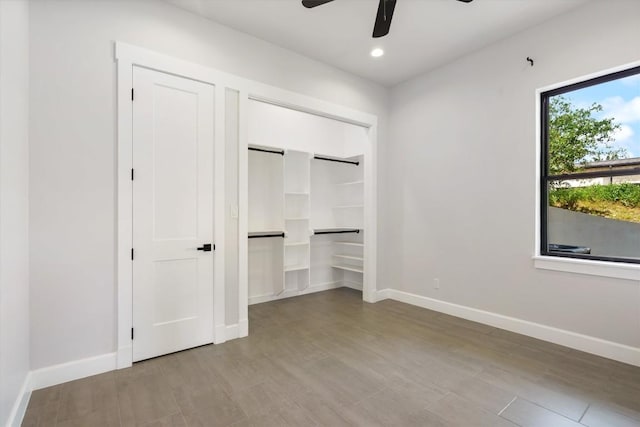 unfurnished bedroom featuring hardwood / wood-style flooring, a barn door, and ceiling fan