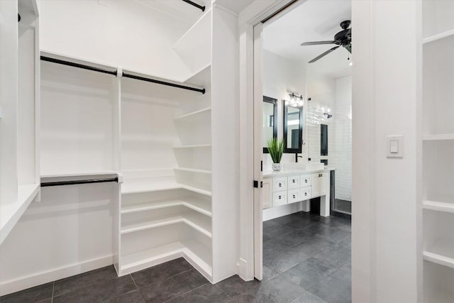 spacious closet featuring dark tile patterned flooring and ceiling fan