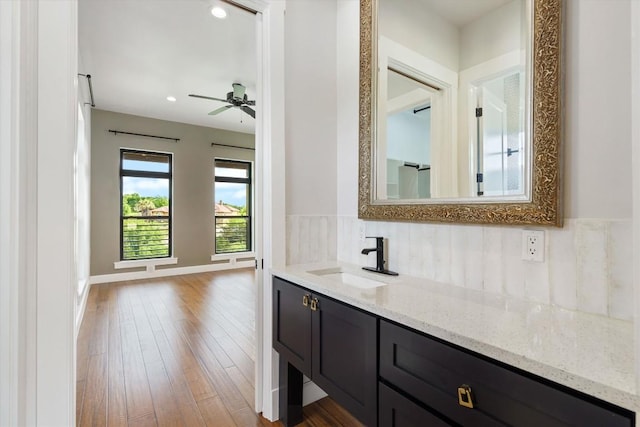 bathroom with vanity, wood-type flooring, tasteful backsplash, and ceiling fan