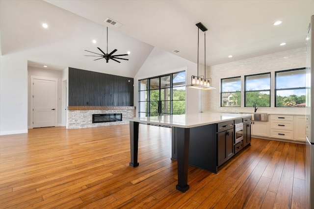 kitchen with light countertops, a glass covered fireplace, light wood-style flooring, a healthy amount of sunlight, and visible vents