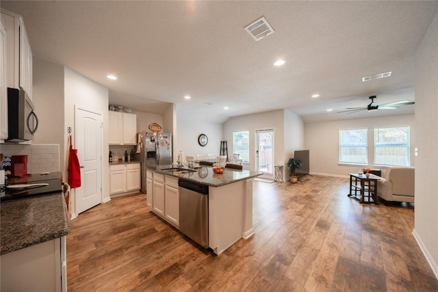 kitchen with appliances with stainless steel finishes, white cabinetry, an island with sink, sink, and dark stone countertops