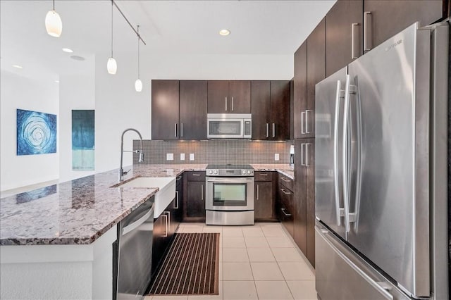 kitchen featuring dark brown cabinetry, sink, light tile patterned floors, appliances with stainless steel finishes, and pendant lighting