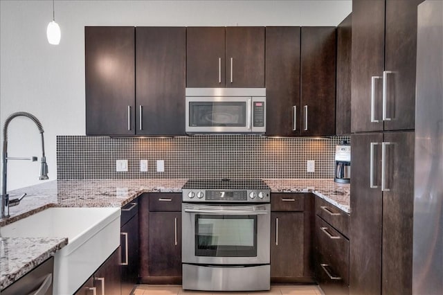 kitchen featuring tasteful backsplash, light stone countertops, appliances with stainless steel finishes, and sink