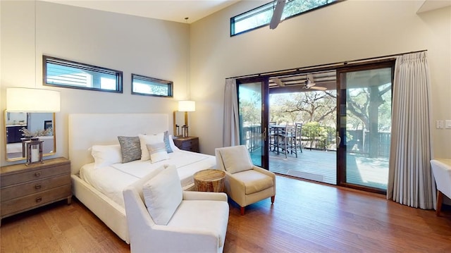 bedroom with hardwood / wood-style flooring, access to outside, and a high ceiling