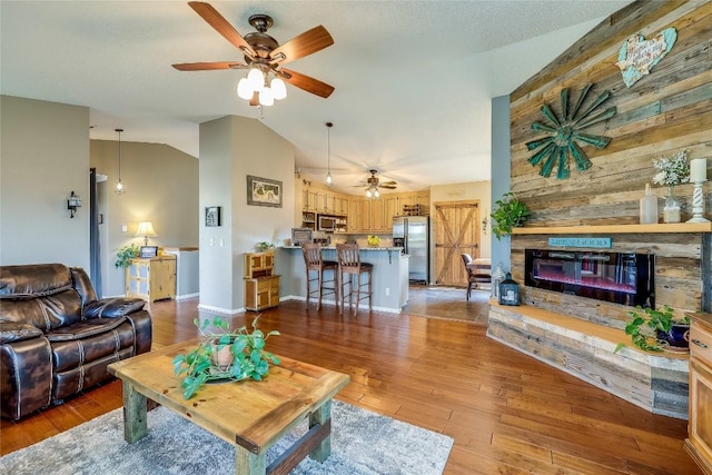 living room with ceiling fan, a fireplace, high vaulted ceiling, and light hardwood / wood-style flooring