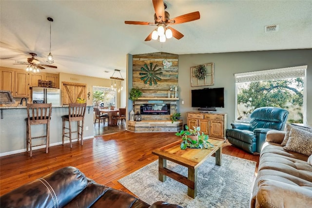 living room with lofted ceiling, a fireplace, wood-type flooring, and ceiling fan