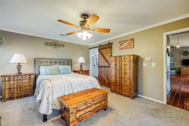 bedroom featuring ceiling fan, ornamental molding, a barn door, and carpet