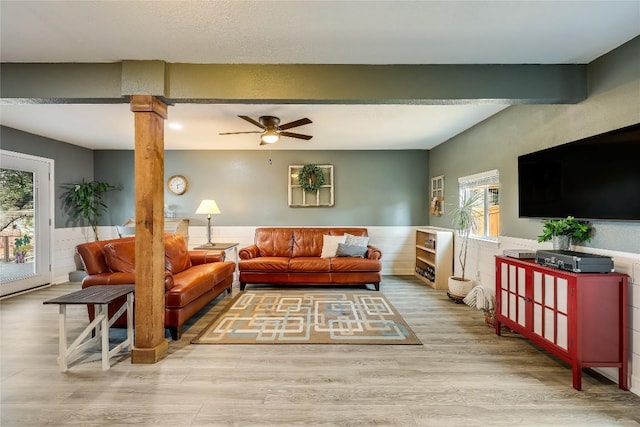 living room with light hardwood / wood-style flooring, beamed ceiling, ceiling fan, and ornate columns