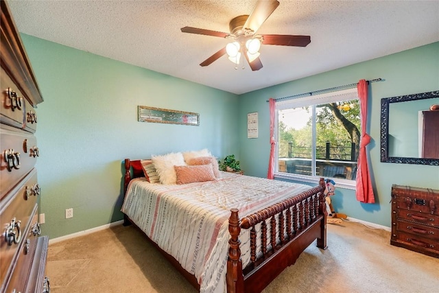 bedroom with ceiling fan, light colored carpet, and a textured ceiling