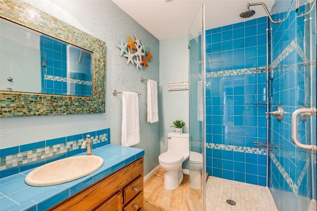 3709 Alamo Cv, Lago Vista, TX 78645 - full bathroom with vanity, toilet, tiled shower, backsplash, and a textured wall