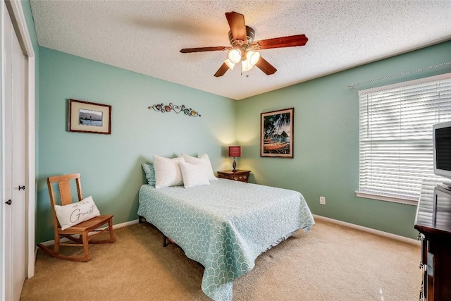 carpeted bedroom with ceiling fan and a textured ceiling