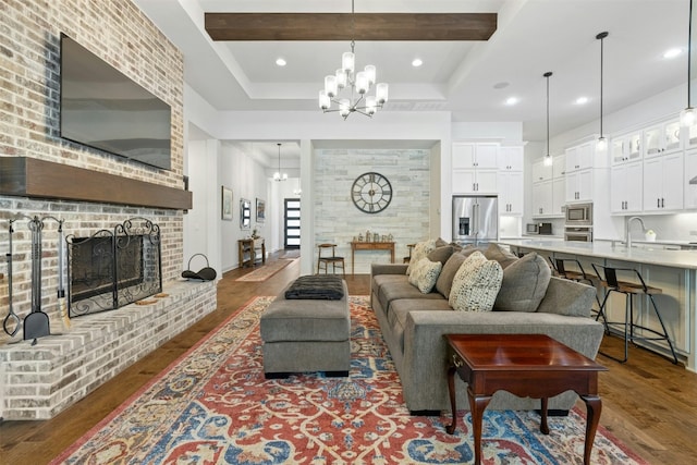 living room featuring sink, dark hardwood / wood-style floors, a chandelier, a fireplace, and beamed ceiling