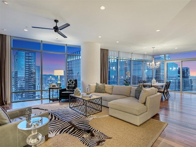 living room featuring hardwood / wood-style flooring, ceiling fan with notable chandelier, floor to ceiling windows, and a healthy amount of sunlight