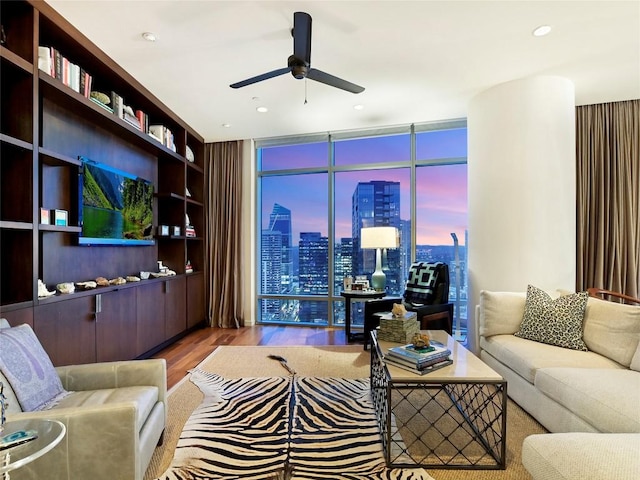 living room with wood-type flooring, expansive windows, and ceiling fan