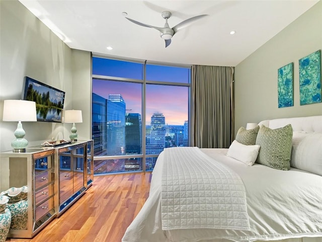 bedroom with floor to ceiling windows, wood-type flooring, and ceiling fan