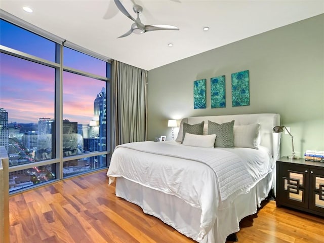 bedroom with expansive windows, hardwood / wood-style flooring, and ceiling fan