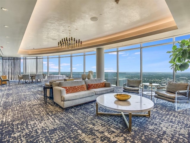 interior space with a tray ceiling, a wall of windows, and a water view