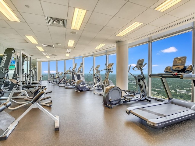 workout area with a drop ceiling and expansive windows