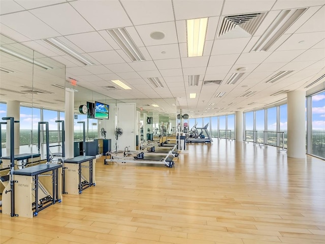 exercise room featuring floor to ceiling windows, a healthy amount of sunlight, and a water view