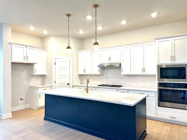 kitchen with pendant lighting, a kitchen island with sink, stainless steel oven, and white cabinets