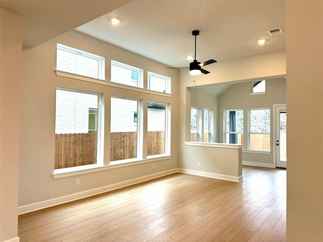 empty room with vaulted ceiling, ceiling fan, and light hardwood / wood-style floors