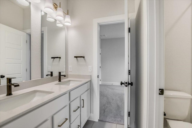 bathroom featuring tile patterned flooring, a sink, toilet, and double vanity