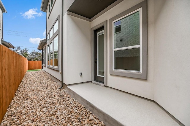 view of property exterior with fence, a patio, and stucco siding