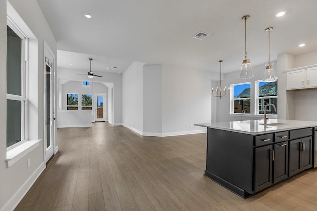 kitchen featuring open floor plan, light countertops, a sink, and light wood-style flooring