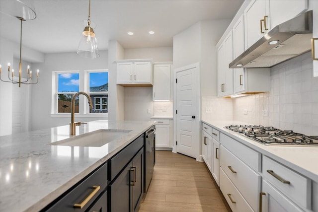 kitchen featuring white cabinets, appliances with stainless steel finishes, decorative light fixtures, under cabinet range hood, and a sink