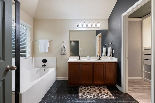 bathroom with lofted ceiling, vanity, and a washtub