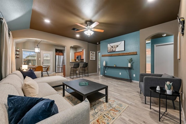 living room featuring light hardwood / wood-style flooring, ceiling fan, and vaulted ceiling