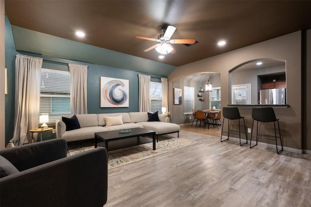 living room with ceiling fan, lofted ceiling, and light wood-type flooring